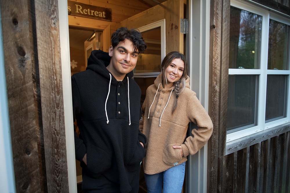 two models wearing hoodies, standing in doorframe