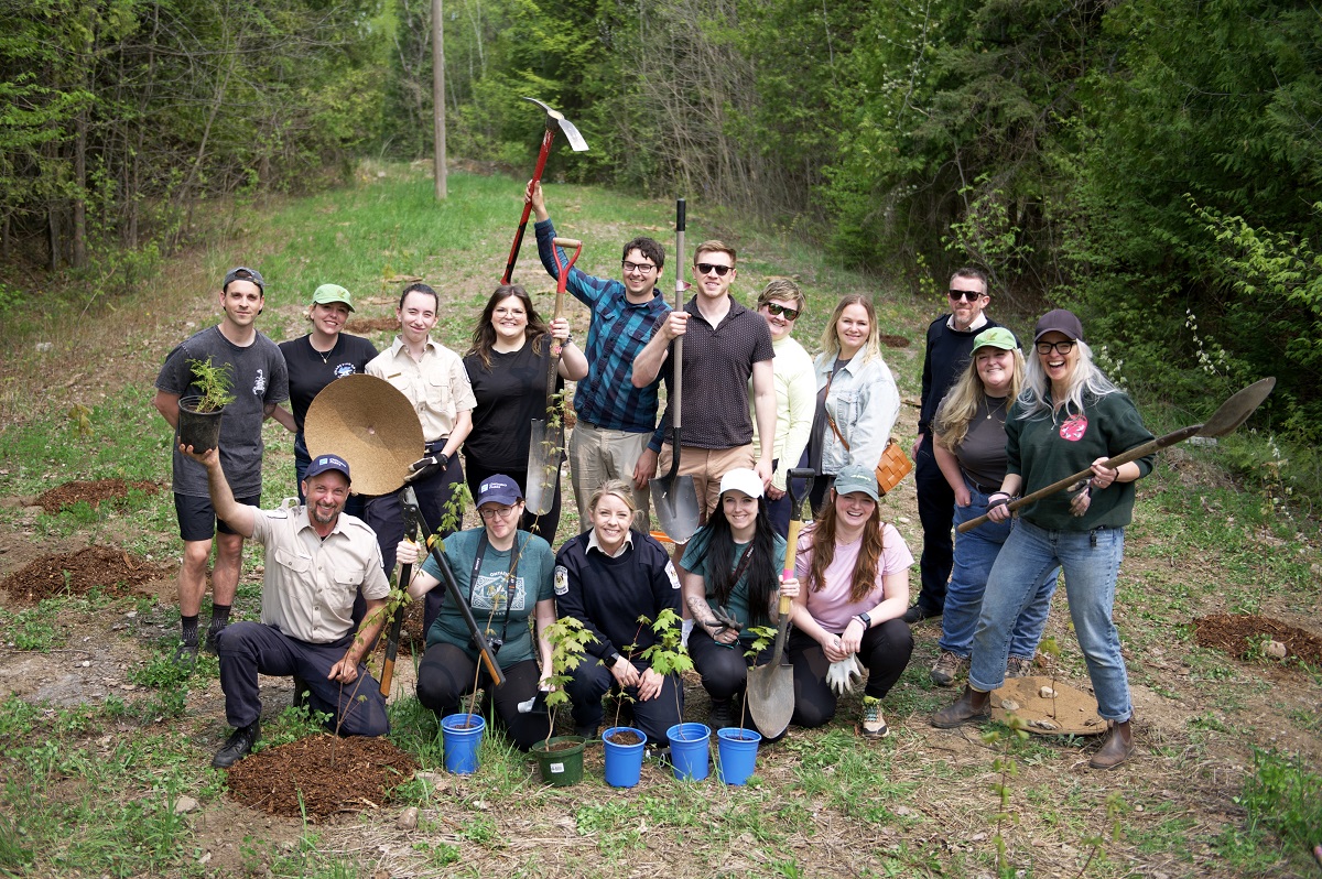 group of staff and volunteers with shovels and baby trees