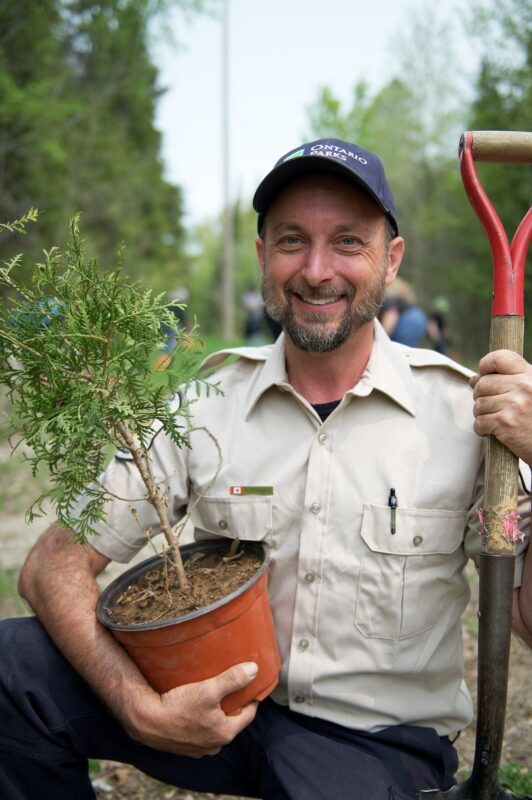 Park staff holds baby tree and shovel