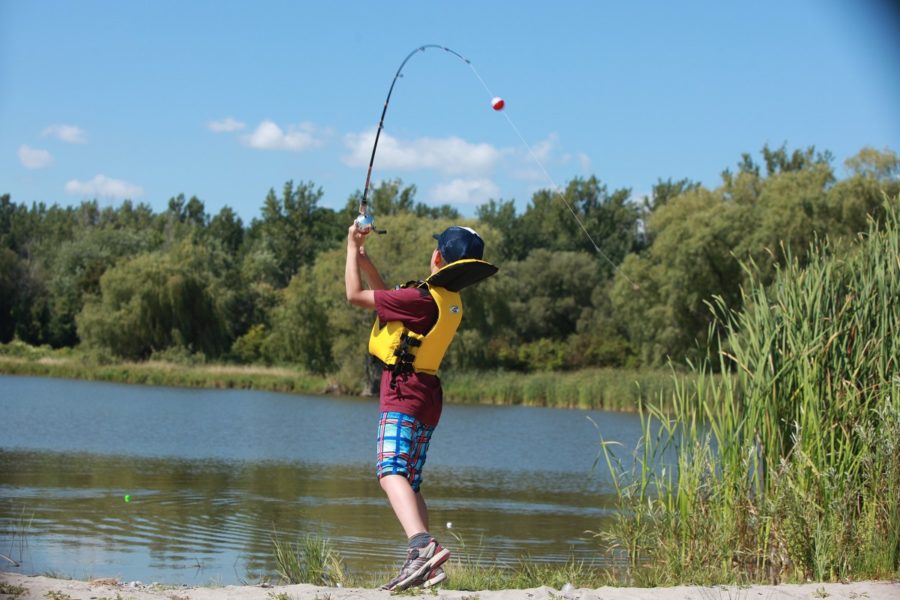 7 or 8 year old, mid cast on a sunny day at a lake