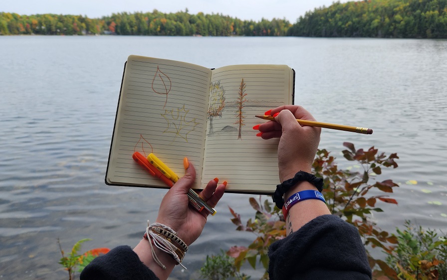 hands holding up journal with fall leaf sketches