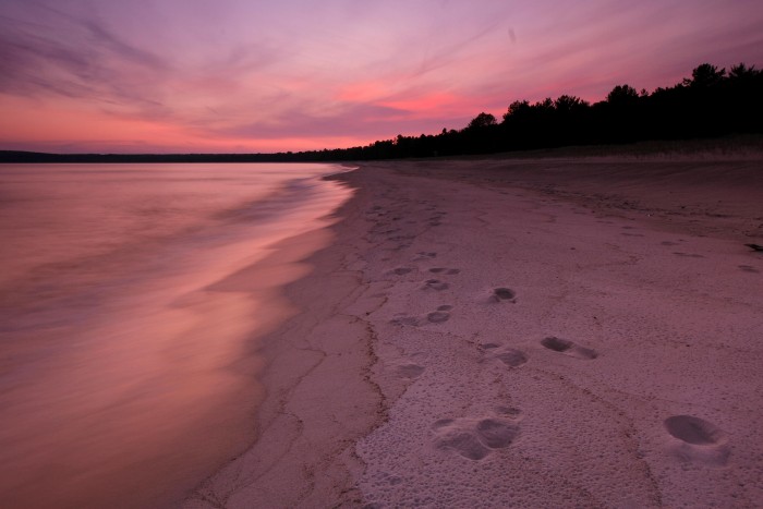 beach with pink sky and footprints in sand