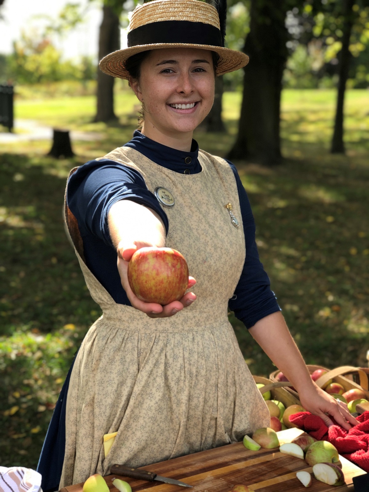 Jess in historial pioneer costume, holding apple