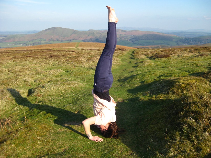 Woman does headstand in field