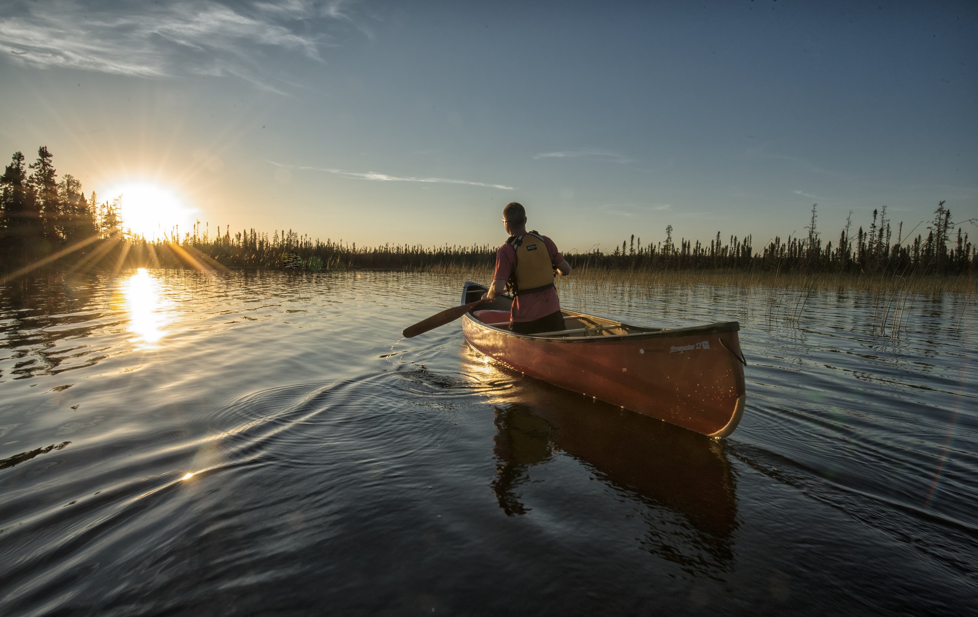 paddler on lake during sunset