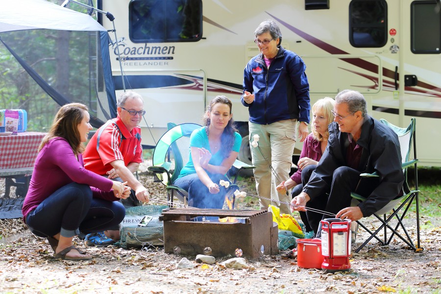 family group gathered around campfire toasting marshmallows. 