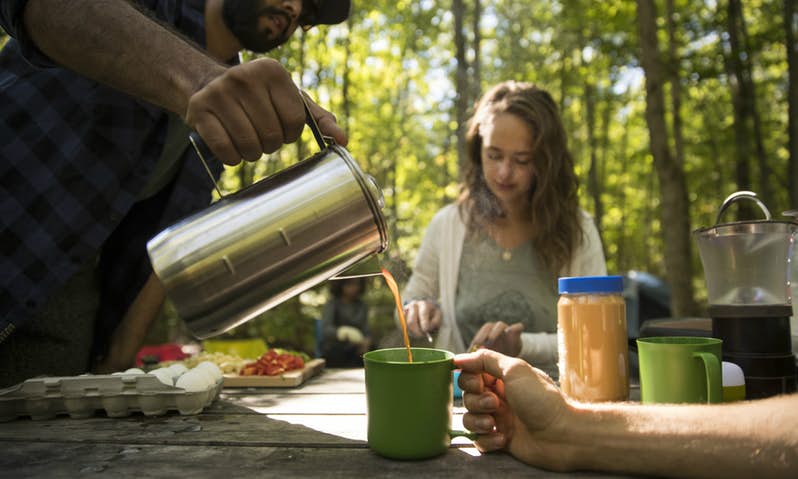 pouring coffee into cup on picnic table