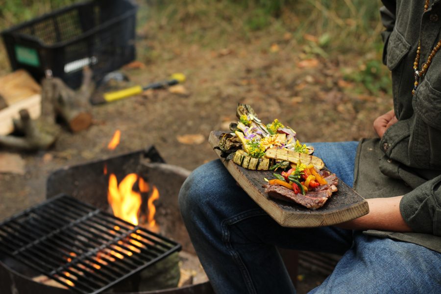 camper eating finished meal beside campfire