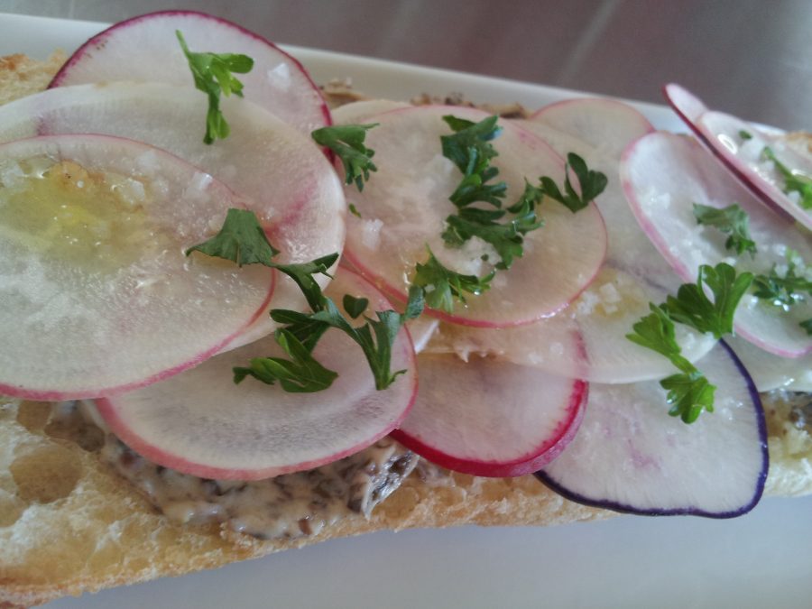 Close up of radishes on a baguette with spread underneath. 