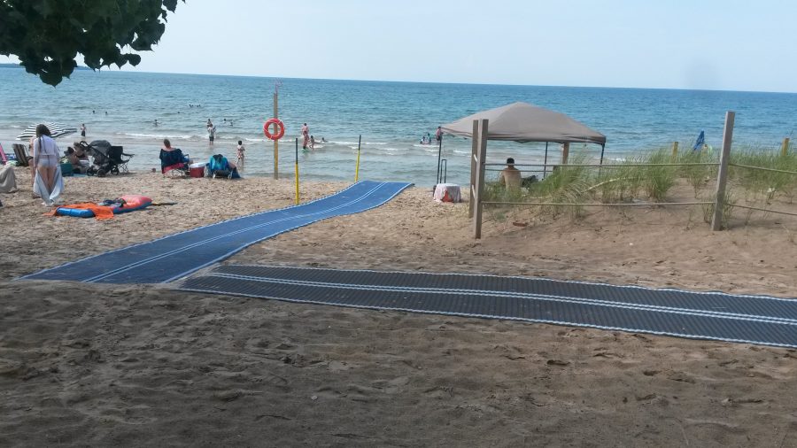 Des tapis de plage sont placés sur le sable menant à l’eau.