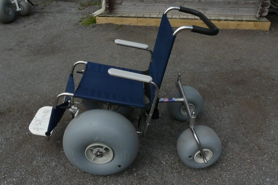 All-terrain beach wheelchair parked on pavement.