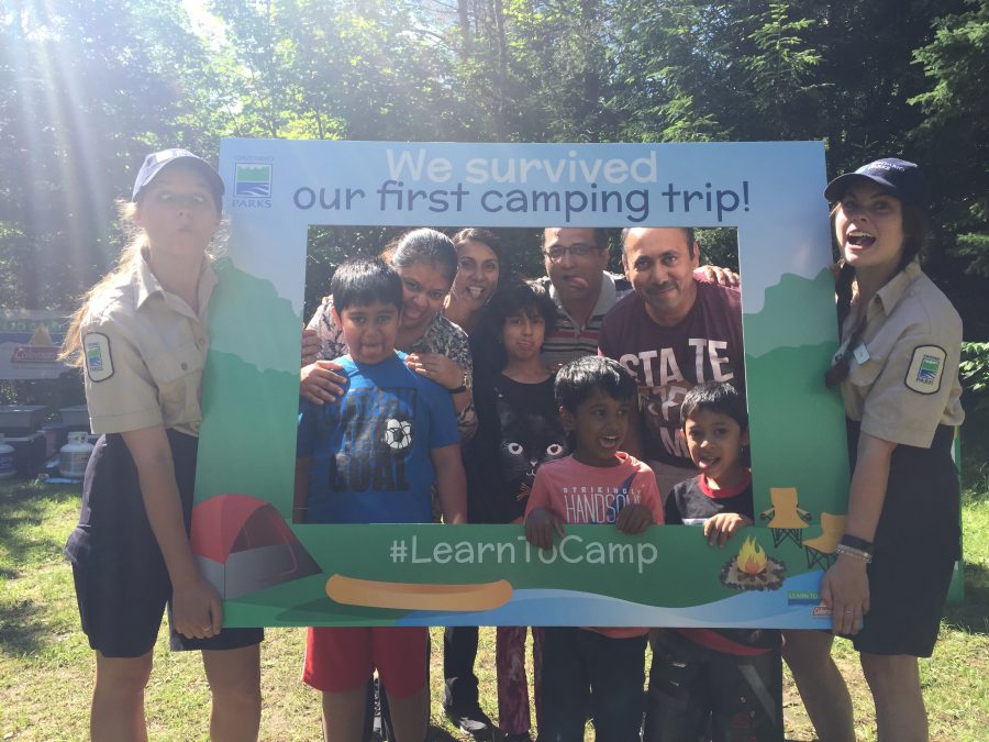 Learn to Camp leaders make funny faces with participants in photo frame. 