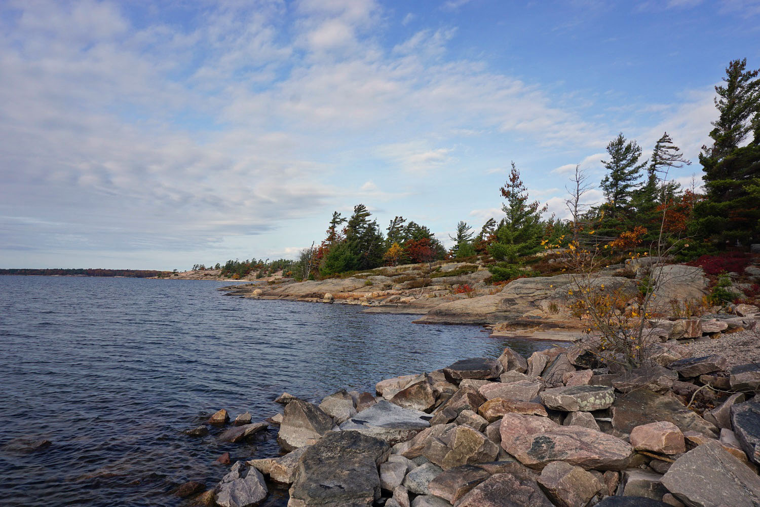 rocky shoreline with blue sky and forests