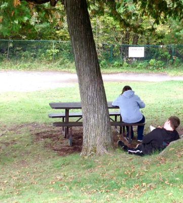 Two students sketch on the grass and table