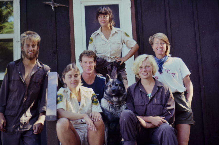 6 Park staff and volunteers from the 80's posing together outside a dark brown cabin