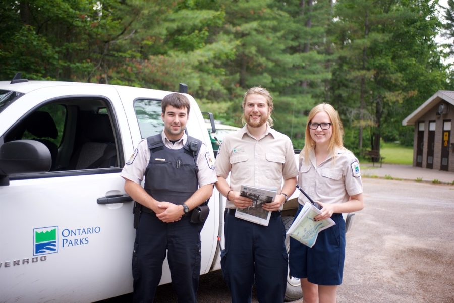 Three park staff standing together in front of truck