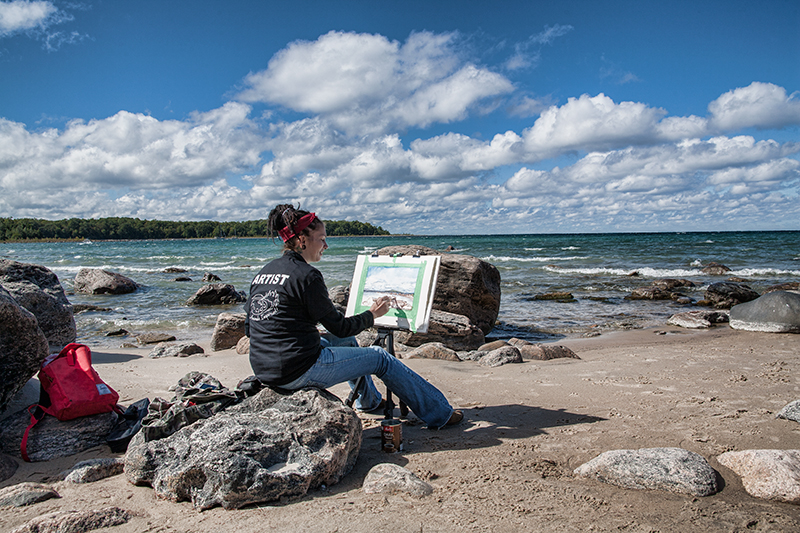 student painting on shoreline