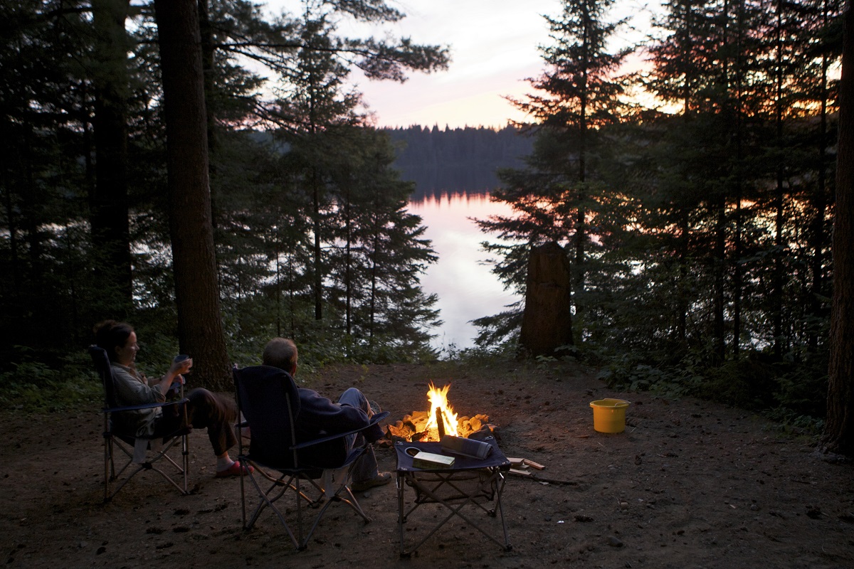 campers around campfire beside lake