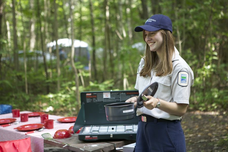 Ontario Parks staff person demonstrating how to cook on a camp stove