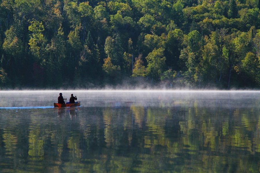 Deux hommes dans un canot pagayent au loin par un matin brumeux