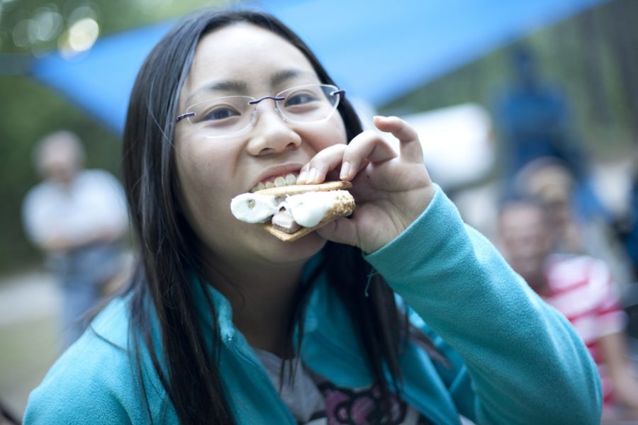 Une femme en train de manger un « s'more » sur un emplacement de camping