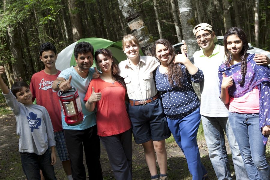 Picture of eight people on a campsite, posing together and giving a thumbs up