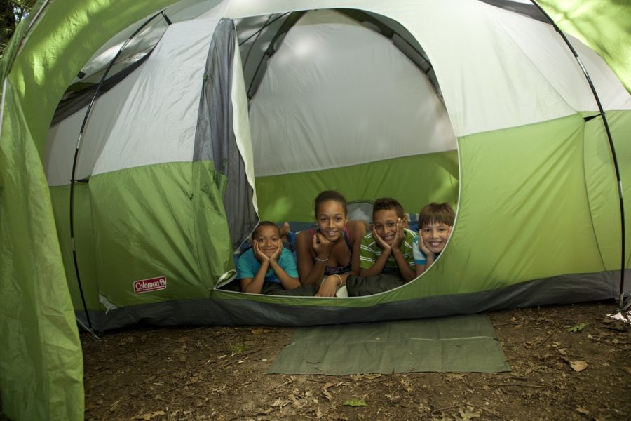 Four kids in a tent, looking out through the unzipped door