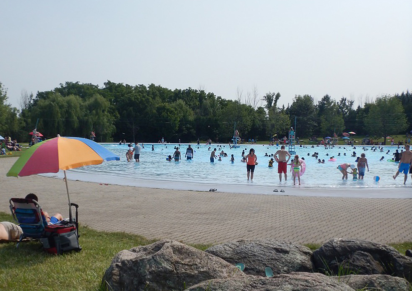 Vue d’ensemble de la piscine avec parasol multicolore dans le coin gauche