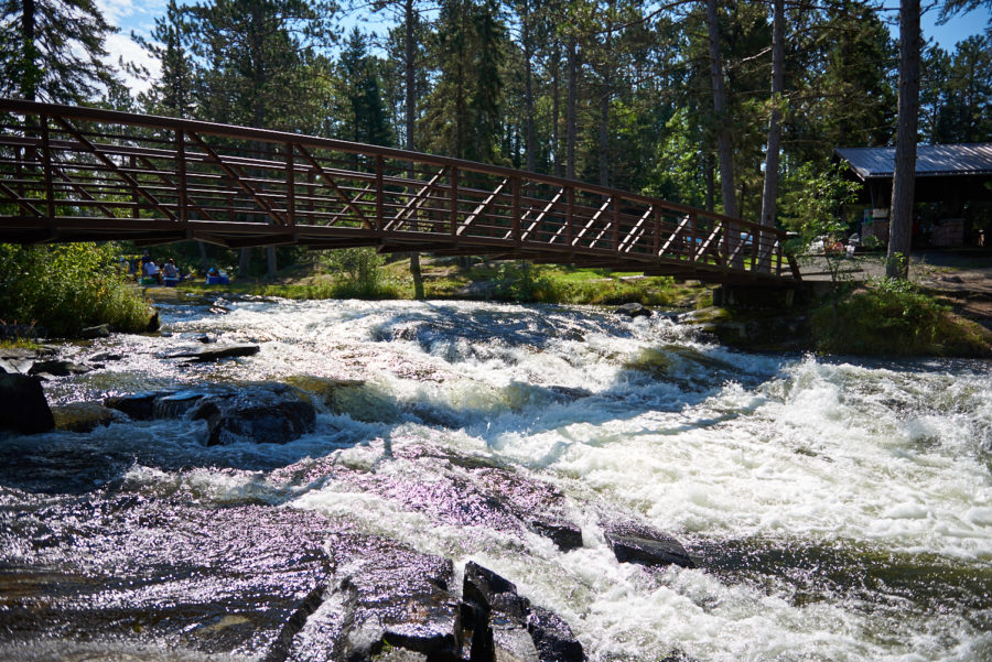 Rivière à l’eau blanche avec un pont qui l’enjambe.