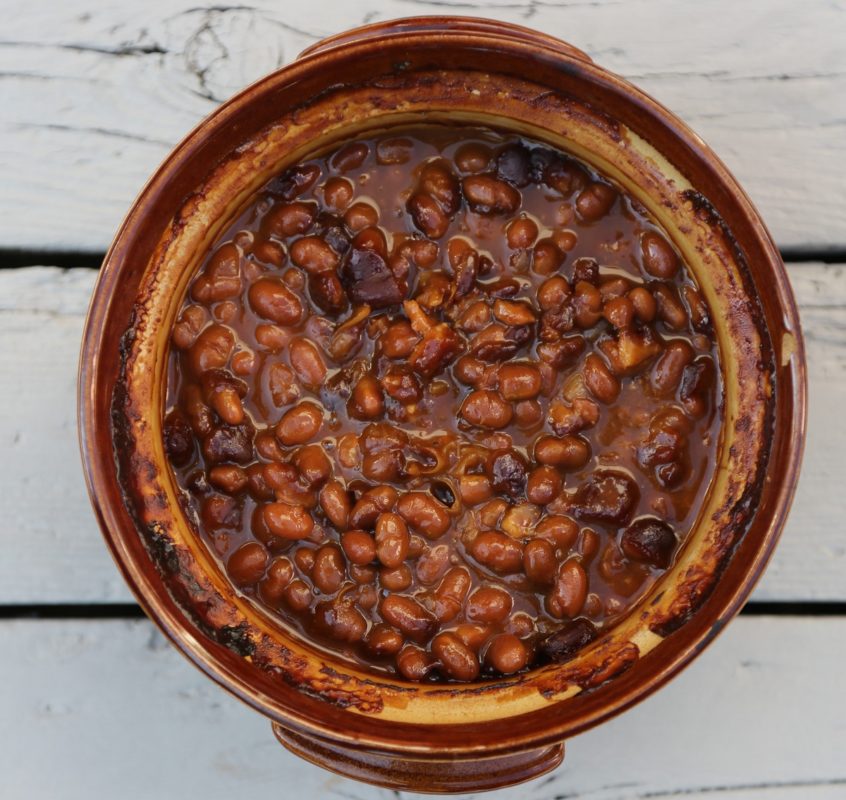 Baked beans in a brown ceramic pot on a grey deck (photo taken from above)