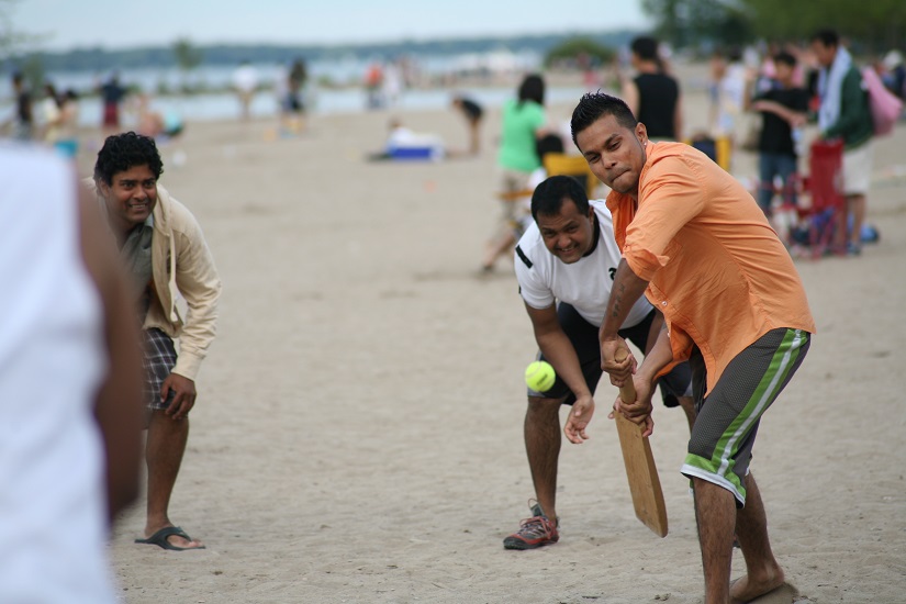 Men playing cricket on the beach