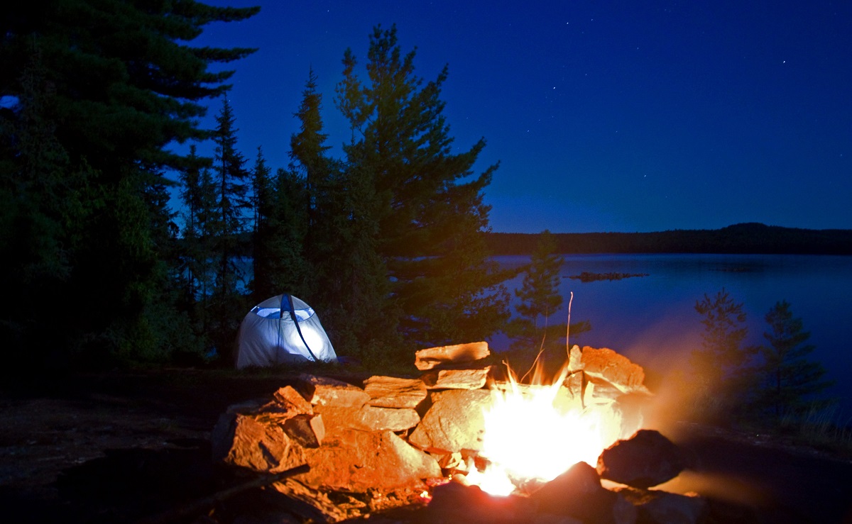 Campsite with campfire going, on a lake