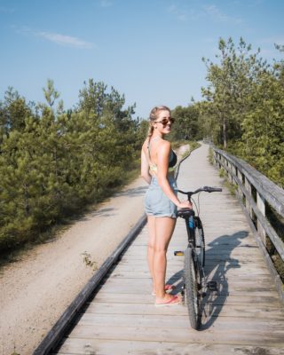 Woman stands with bike on trail