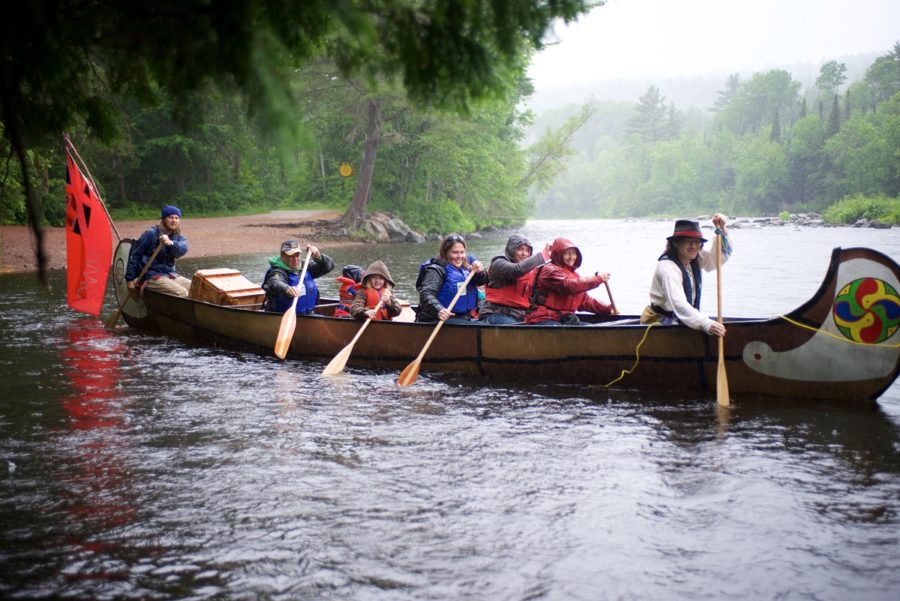 Group in a voyageur canoe with a costumed staff member at the front of the canoe