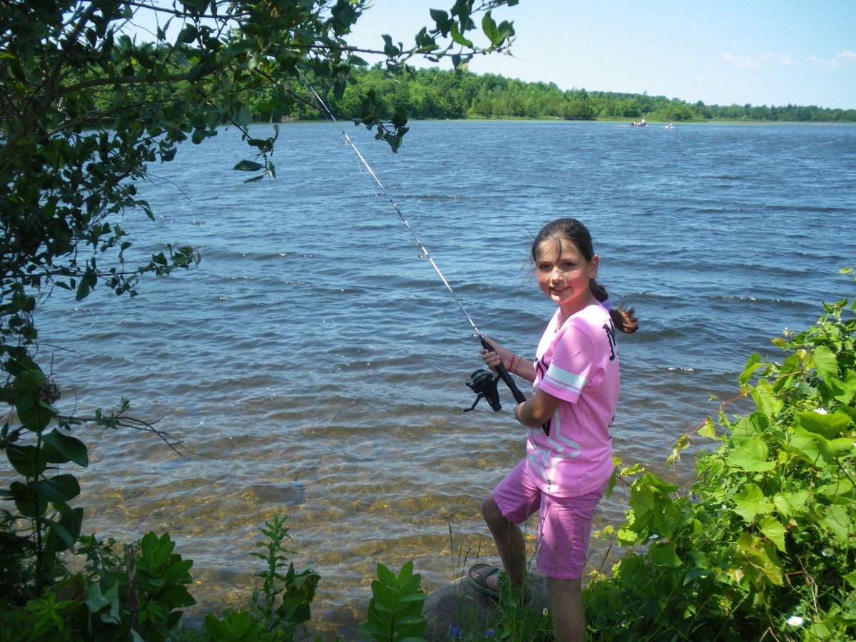Little girl fishing on shore of a big water body