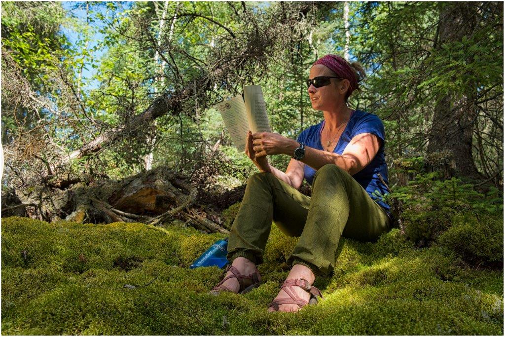 Femme lisant un livre, assise dans la forêt