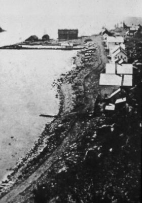 Black and white photo of shoreline with buildings along