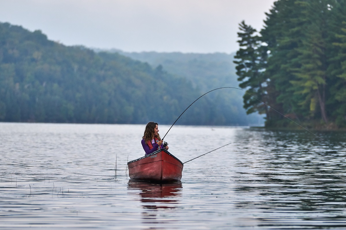 Jeune femme pêchant dans un canot sur un lac