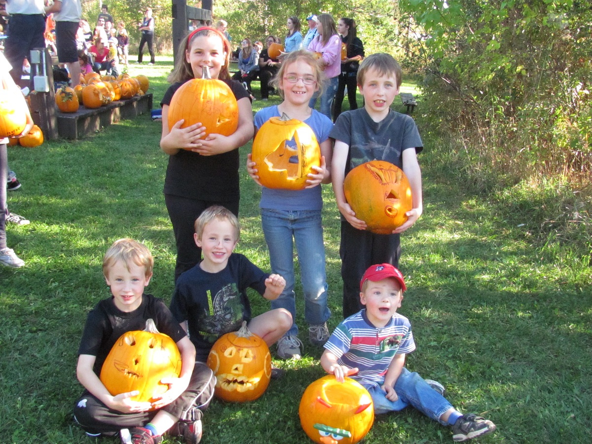 Six kids hold jack-o-lanterns up