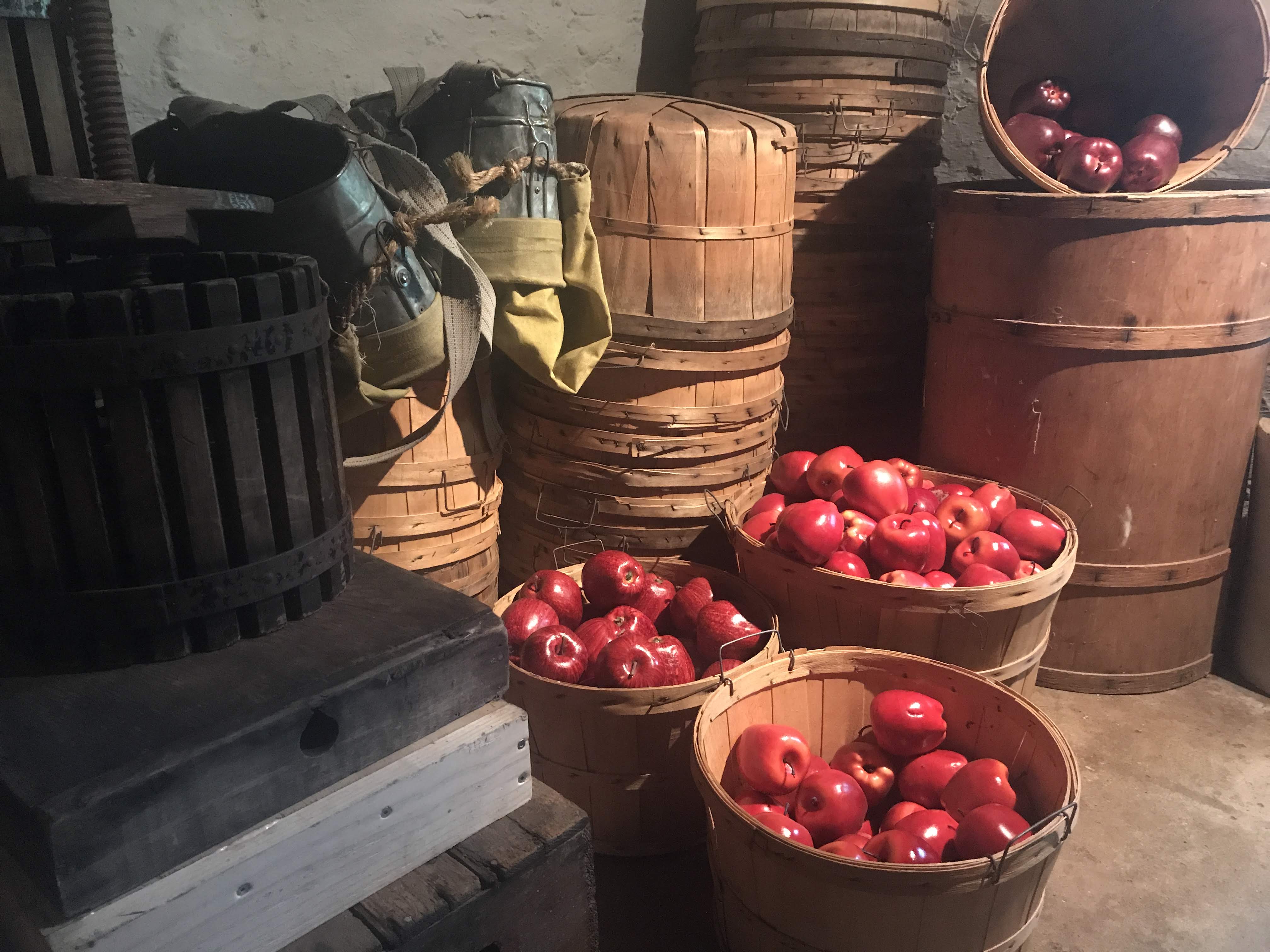 Three baskets of apples in the foreground of stacked baskets