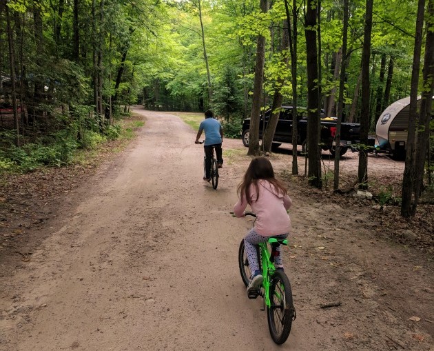Vue de dos de deux personnes faisant du vélo sur un sentier dans la forêt 