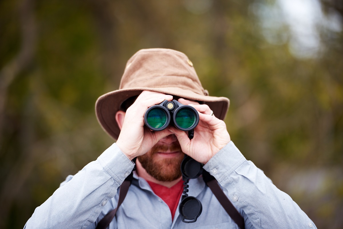Guy with binoculars and tilley hat