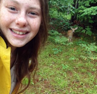 Girl taking a selfie of herself in front of a doe or fawn