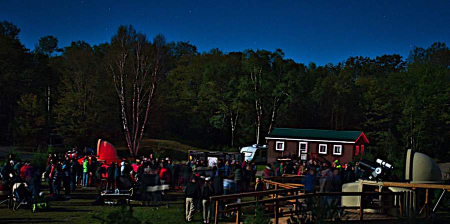 people in field at nght with telescopes