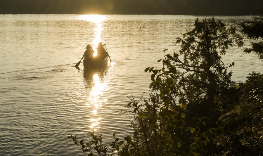 Two figures sillouetted in a canoe at sunset