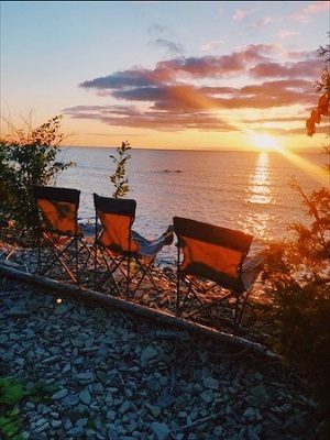 Trois fauteuils pliants sur la plage au coucher du soleil.