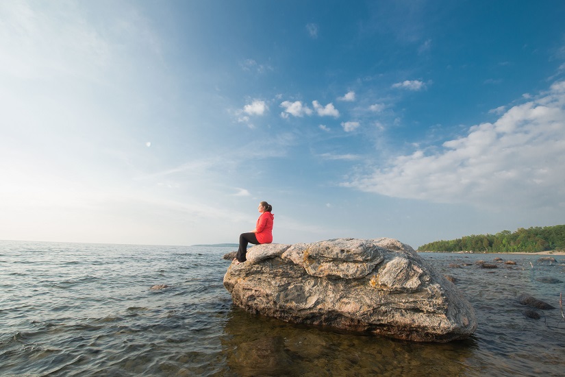 Woman sits on rock in lake