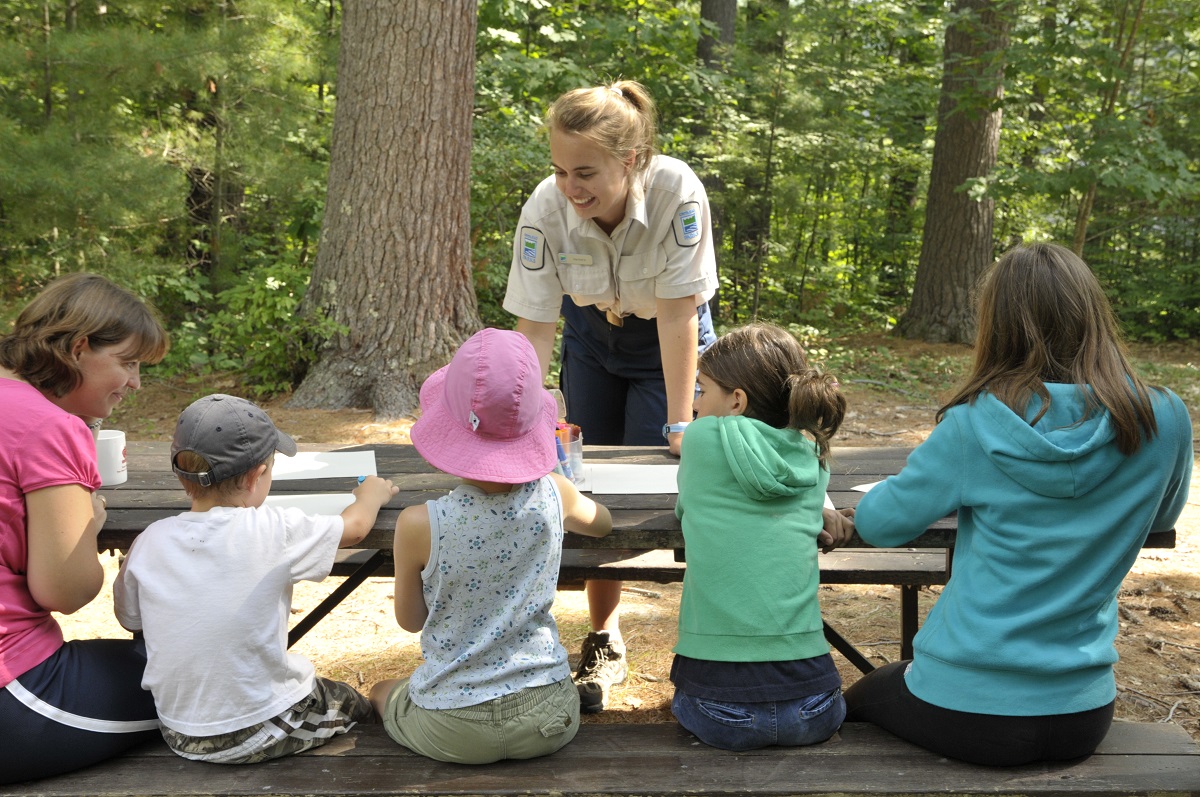 Five kids at a picnic table with an NHE leader facing them