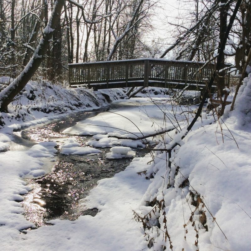 Pont au-dessus d’une rivière gelée, recouverte de neige