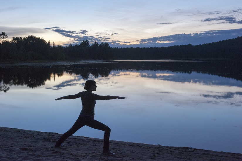 Une femme faisant du yoga sur la plage au coucher de soleil